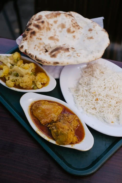 A beautifully plated dish of Achar Gosht masala with naan or paratha