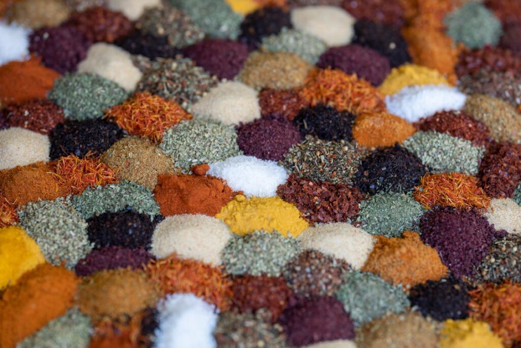 A bowl of freshly ground Hazir spices in the middle of an assortment of whole spices turmeric cumin seeds coriander