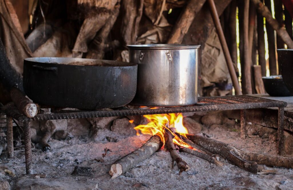 A clay pot simmering over a low flame cooking a traditional curry