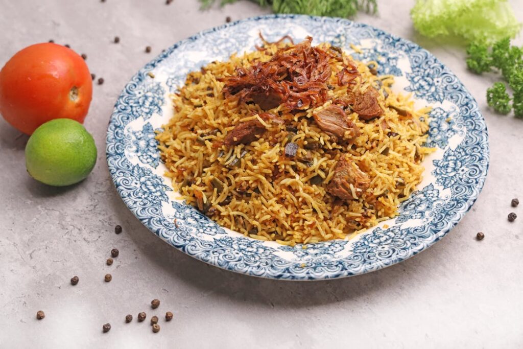 A close up of a plate of Pulau Biryani recipe with golden rice caramelized onions and herbs