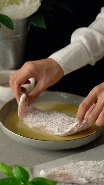 Showing steps like seasoning the chicken coating with flour frying and the final presentation