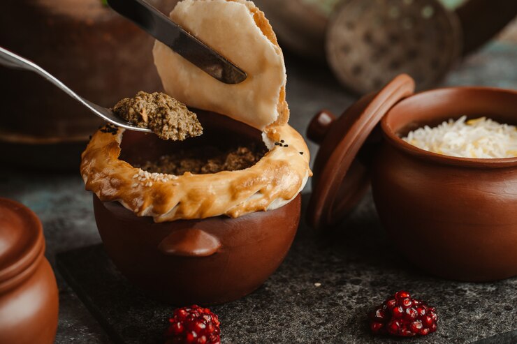 A traditional clay pot or heavy bottomed pan filled with simmering keema to show the slow cooking process