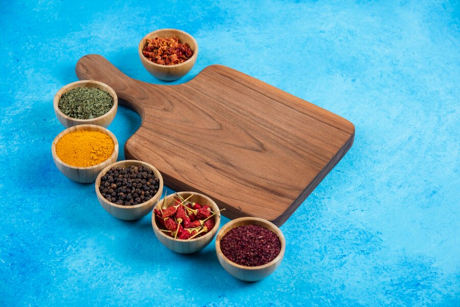 A vibrant display of common Pakistani spices like cumin turmeric coriander and garam masala in small bowls or on a wooden board