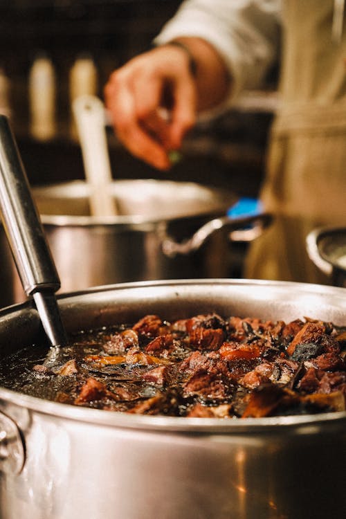 Show the slow cooking of Nihari in a pot with close ups of the rich simmering gravy